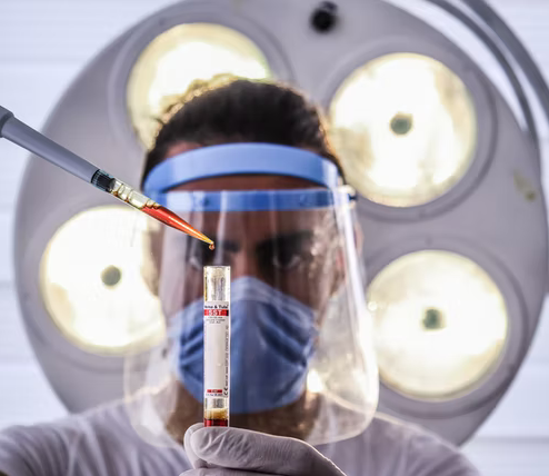 A male doctor dropping a blood drop in a test tube.